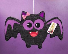 a bat hanging on a purple wall with a tag