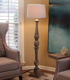 a living room with two chairs and a lamp in front of a painting on the wall