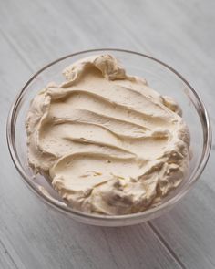 a bowl filled with cream sitting on top of a wooden table