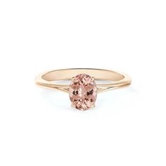 a gold ring with an oval morganite stone in the center, on a white background