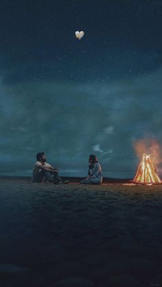 two people sitting next to a campfire under a night sky with a heart shaped balloon