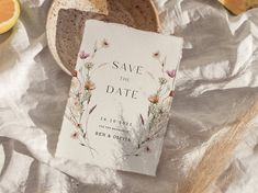 a save the date card sitting on top of a table next to sliced oranges