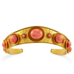 a gold cuff with pink stones on the sides and two circles in the middle,