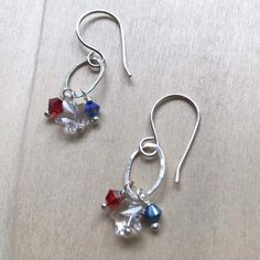 Independence EarringsMaterial: Sterling Silver, Clear Swarovski Star Crystals, 4mm Red and Blue CrystalsTexture: Hammered Finish: High PolishEarring Length: 1 1/2"Created: The oval links used were created using wire that was formed into ovals, soldered, hammered, then polished. The earrings were then assembled using handmade sterling silver ear wires and headpins. Packaging: All orders are elegantly packaged in a hand stamped jewelry box tied with ribbon. Perfect and ready for gift giving! If yo 4th Of July Earrings, Patriotic Earrings, Silver Earrings Handmade, Handmade Beaded Jewelry, Crystal Stars, Earrings Crystal, Hand Stamped Jewelry, Earrings Red, Geometric Necklace