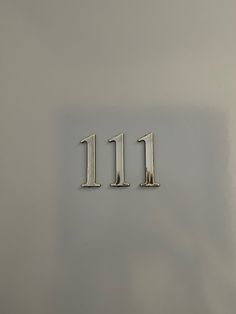 the number 11 is made from metal and sits on a gray surface in front of a white wall