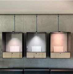 three metal urinals mounted to the side of a wall next to black benches