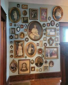 a wall with many different pictures and frames hanging on it's side, along with a wooden door