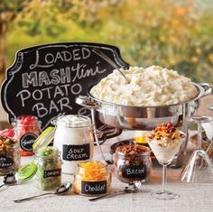 mashed potatoes and other foods on a table in front of a chalkboard sign