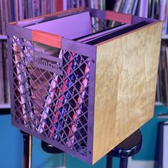 a purple basket sitting on top of a metal stand in front of a book shelf