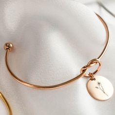 a close up of a bracelet on a white cloth with a gold plated charm