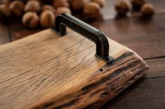 a wooden cutting board sitting on top of a table next to nuts and a knife