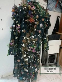 the back of a woman's dress with flowers and shells on it in front of a mirror