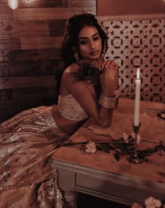 a woman sitting at a table with a candle in her hand and flowers on the table