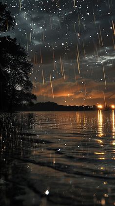 the sky is filled with stars and rain as it shines in the distance over water