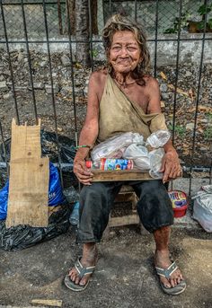 an old woman sitting on a bench with food in front of her and garbage behind her