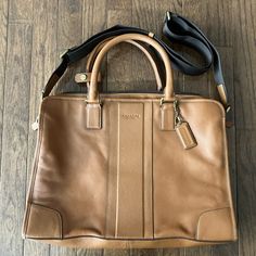 Brand New - Never Been Used. Outside: Brown Leather Inside: Brown Fabric With Zip Top Closure And Multi-Function Pockets. Handles With 4 3/4" Drop Detachable Strap For Shoulder Or Crossbody Wear. 15 5/8" (L) X 11 1/4" (H) X 3" (W) Designer Tan Satchel For Travel, Designer Business Briefcase With Branded Hardware, Business Leather Bags With Branded Hardware, Designer Briefcase With Gold-tone Hardware For Daily Use, Designer Travel Briefcase With Branded Hardware, Designer Travel Briefcase With Adjustable Strap, Formal Leather Briefcase With Branded Hardware, Leather Briefcase With Branded Hardware For Daily Use, Modern Travel Satchel With Branded Hardware