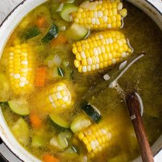 corn on the cob soup in a pot with a wooden spoon