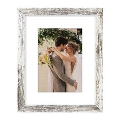 a bride and groom embracing each other in front of a white wall