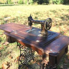 an old sewing machine sitting on top of a table in the middle of a field