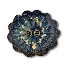 a blue flower shaped dish with pearls and gold jewelry on it's center piece