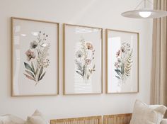 three framed pictures hang on the wall above a couch in a room with white walls