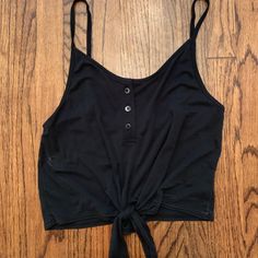 Black Tank Top With Buttons And A Tie At The Bottom. Tags On. Never Worn. Black Crop Top Tank Top For Beach, Urban Outfitters Sleeveless Black Crop Top, Black Cropped Tank Top For Spring, Casual Black Crop Top For Night Out, Urban Outfitters Black Tank Top For Spring, Black Tank Top For Summer Day Out, Urban Outfitters Black Casual Crop Top, Black Cotton Tank Top For Day Out, Urban Outfitters Black Crop Top For Summer