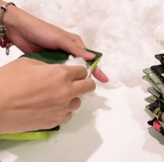 a person is cutting paper with scissors on a white surface next to some other items