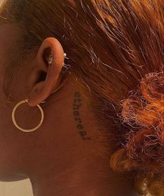 a close up of a person's ear with tattoos on her back and behind the ear