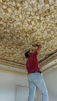 a man working on a ceiling with gold flowers