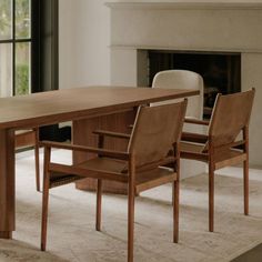 a dining room table with two chairs and a fireplace in the background at one end