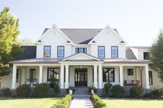 a large white house with lots of windows on the front and side of it's porch