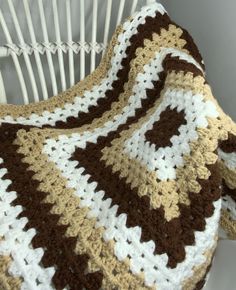 a crocheted blanket sitting on top of a white chair