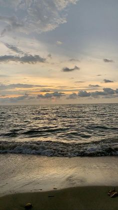 the sun is setting over the water at the beach