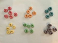 four different colored donuts on a white surface