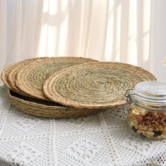 two wicker trays sitting on top of a table next to a jar filled with nuts