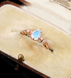 an opalite and diamond ring sitting on top of a wooden box