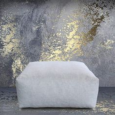 a white couch sitting on top of a floor next to a wall covered in gold paint