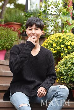 a young man sitting on the steps in front of some potted plants and smiling