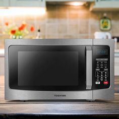 a stainless steel microwave oven sitting on top of a wooden countertop in a kitchen