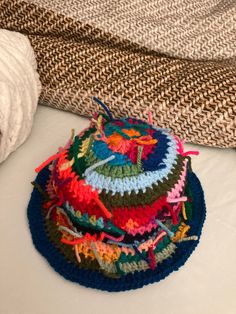 a pile of multicolored crocheted hats sitting on top of a bed