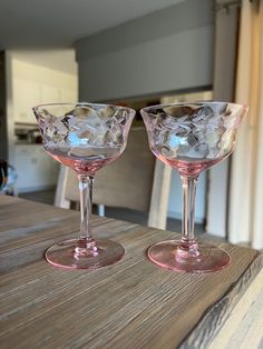 two empty wine glasses sitting on top of a wooden table next to a kitchen counter