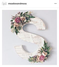 the letter s is decorated with flowers and greenery on top of sheet music sheets