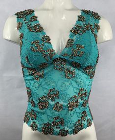 Hand decorated sleeveless lace top in Green and Copper Gold color combination on floral patterned lace with shiny sequins and beads. Perfect for any occasion. 1. Available in four sizes: S, M, L, and XL. 2. Has three rows of hooks-eye position at the back which makes it easy to fit perfectly in your body. 3. Made from stretch lace which helps you easily adjust to your body size. 4. Individually hand beaded.5. Light in weight and comfortable to wear.6. Has cotton lining in the inner bust area to Lace Cami Tank Top For Party, Lace V-neck Tank Top For Party, Glamorous Embellished Sleeveless Crop Top, Fitted V-neck Lace Top For Party, Embellished V-neck Tank Top For Party, Summer Party Lace Camisole Top, Elegant Party Camisole Crop Top, Glamorous Fitted Crop Top Tank Top, Party Lace Cami Crop Top