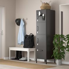 a locker and coat rack in the corner of a room next to a potted plant