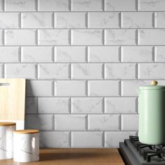 a stove top oven sitting in front of a white brick wall next to two wooden stools