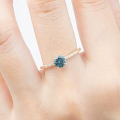 One of a kind ring In stock ready to ship in size 7 0.75ct 5.5mm teal blue Montana sapphire 0.03ctw G color SI clarity accent diamonds Band width: approx. 1.4mm Low profile four prongs basket setting Made of 100% recycled solid 14k yellow gold and ethically sourced gemstones Packaged in a white craft paper ring box Blue Round Cut Diamond Ring, Blue Diamond Ring With Round Cut, Blue Emerald Cut Diamond Ring, Blue Diamond Birthstone Ring For Promise, Blue Birthstone Ring With Ethical Diamonds, Blue Diamond Birthstone Promise Ring, Blue Sapphire Diamond Ring For Proposal, Gift Sapphire Diamond Ring, Lab-created Sapphire Diamond Ring For Promises