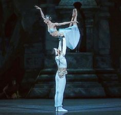 two ballerinas are performing on stage with their arms in the air