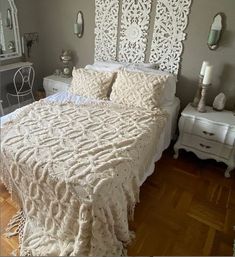 a white bed sitting on top of a wooden floor next to a dresser and mirror