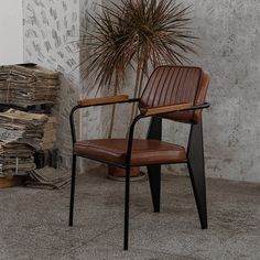 a brown leather chair sitting next to a potted plant