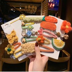 a person holding up a bunch of crocheted items on top of a piece of paper